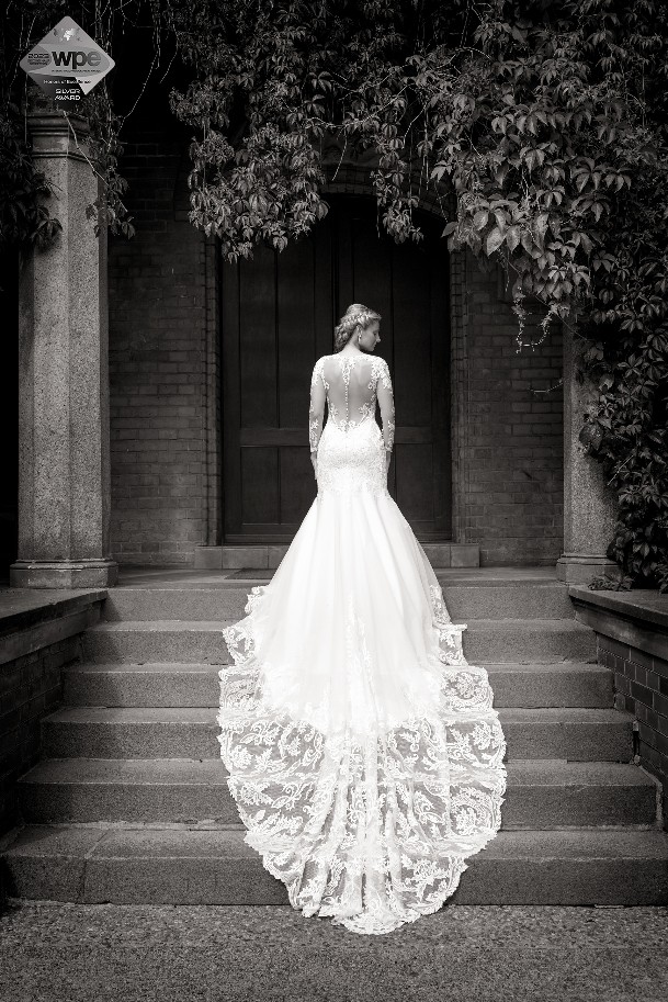 panna młoda stoi tyłem na schodach w pięknej sukni ślubnej